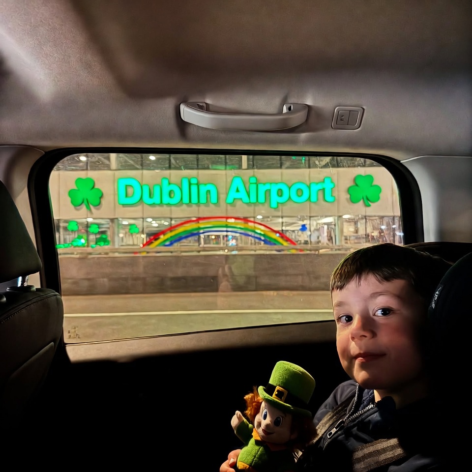 Child in rear-facing car seat inside taxi at Dublin Airport during St Patrick’s Day airport transfer